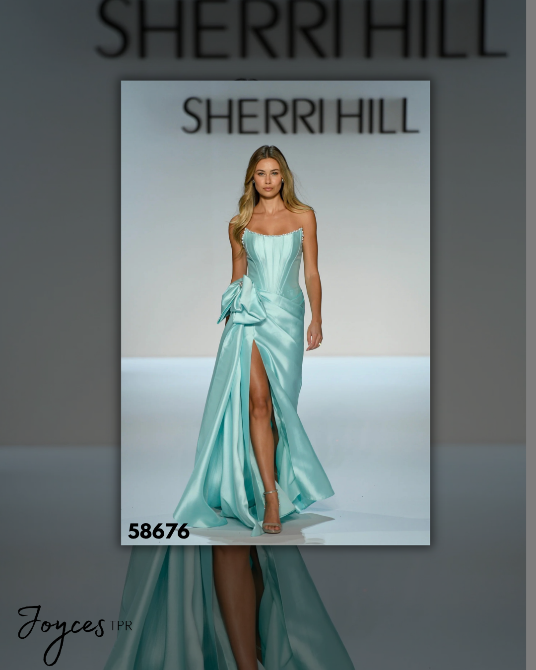 Shop Sherri Hill 58676, a strapless fitted corset gown with a statement bow, dramatic side cape and skirt slit at Joyce’sTPR.